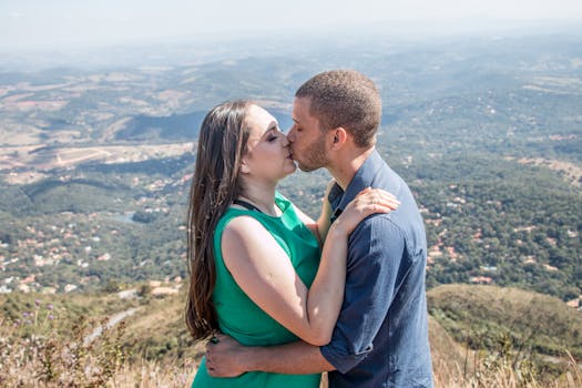 A couple shares a romantic kiss with a breathtaking view of Belo Horizonte's mountainous landscape.