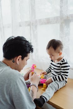 A father and his young son enjoying quality playtime together indoors with colorful toys.